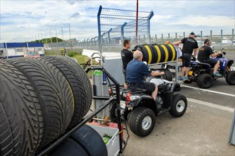 Car racing team moves mobile racks of racing tyres in grid lane to the starting grid
