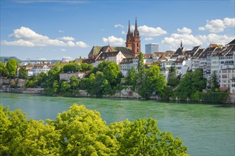 View of the Basel Cathedral in the middle of the old town of Basel with the turquoise Rhine River in the foreground