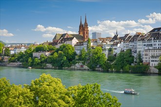 View of the Basel Cathedral in the middle of the old town of Basel with the turquoise Rhine River in the foreground