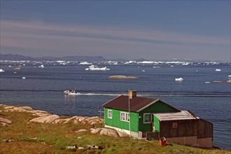 Simple dwelling house on the edge of an iceberg-covered bay