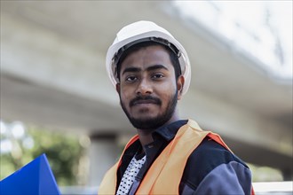 Young technician with beard outside with helmet working on a bridge