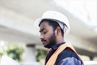 Young technician with beard outside with helmet workingenda on a bridge
