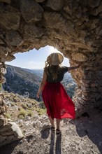 Young woman looking through hole in castle wall