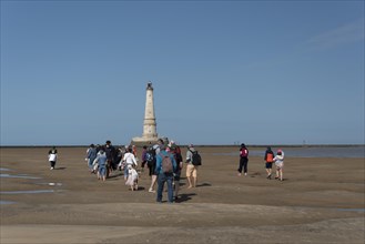 Tourists walk to Cordouan lighthouse at low tide