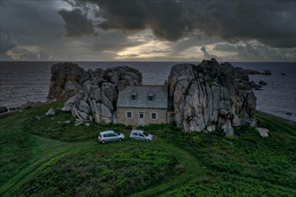 Drone shot from the mainland of the house between the rocks (Le gouffre de Plougrescant) with dramatic sky and the Atlantic Ocean