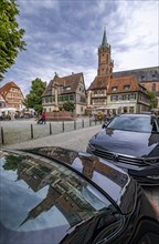 The market square with St. Mary's column at the fountain and the tower of the Catholic Church of junglefowl (Gallus) reflected on the bonnet of a car