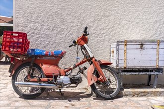 Old red scooter in front of a wall