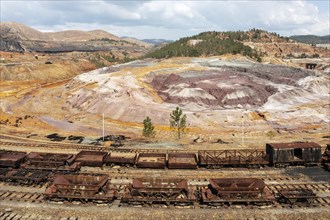 Disused wagons at the dramatically scarred landscape of mineral-rich ground and rock at the Rio Tinto mines