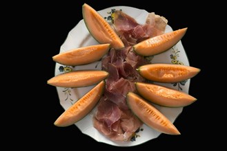 Ham and honeydew melon served on a plate