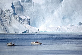 Boat in front of huge iceberg