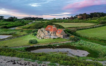 Drone shot of a farmhouse on granite cliffs on the coast of Plougrescant