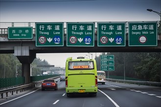 Bus travelling on 3-lane motorway with signs and a bridge