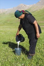Kyrgyz woman pouring mare's milk into a bucket