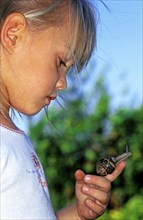 Girl with brown garden snail helix aspersa on her finger