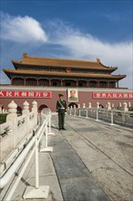 Policeman standing in front of a picture of Chairman Mao at the gate to the Forbidden City