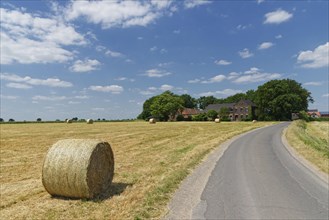 Farm house with harvested cornfield and bales of straw