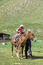 Kyrgyz man helping his girl on a horse