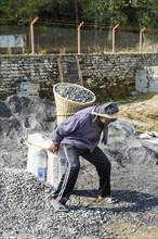 Nepalese man carrying stones for construction on his back
