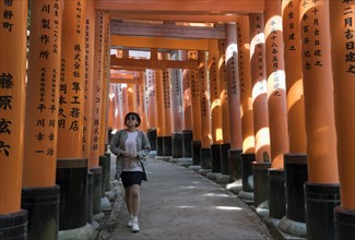 Young woman on a pathway lined with torii gates