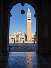 View through an archway onto St Mark's Square with the Campanile bell tower and the Basilica of St Mark