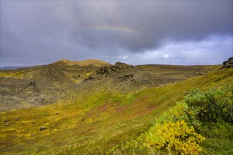Rainbow over volcanic landscape and colourful autumn colours