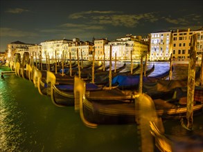 Gondolas in front of historic house facades in the Grand Canal at night