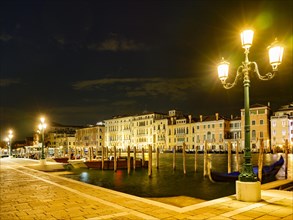 Boat mooring in front of historic house facade on the Grand Canal at night