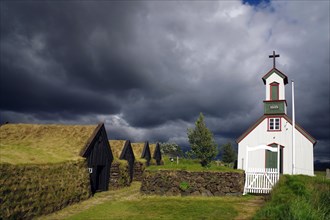 Wooden church and peat houses against dark clouds