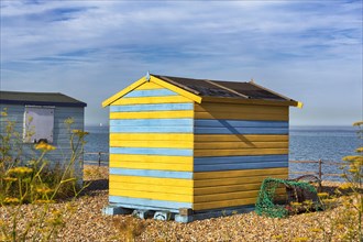 Colourful beach huts with fish trap by the sea