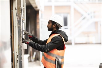 Technician with beard and helmet works in a workshop