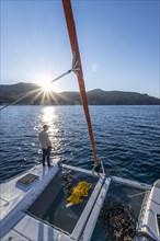 Young man standing on a catamaran looking into the sunset