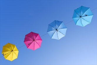 Coloured umbrellas against a blue sky