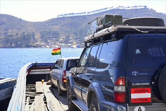 Austrian off-road vehicle on a simple ferry boat across the Strait of Tiquina