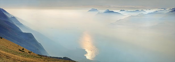 Lake Garda in the morning mist with Lake Garda mountains and Bergamo Alps