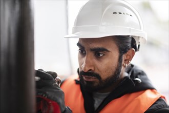 Technician with beard and helmet works in a workshop