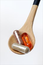 Capsules with food supplement and omega-3 fatty acid in wooden spoon