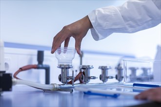 Hand of a laboratory assistant with laboratory glass working in a laboratory with laboratory equipment