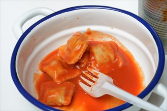 Ravioli with tomato sauce in bowl with plastic fork