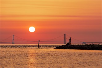 Silhouette of two men fishing with the Great Belt Bridge in the background