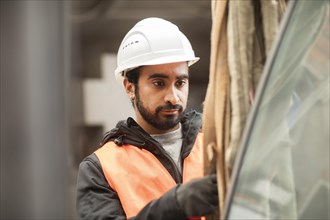 Technician with beard and helmet works in a workshop