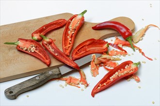 Red sliced peppers on wooden board with knife