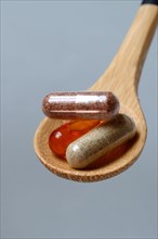 Capsules with food supplement and omega-3 fatty acid in wooden spoon
