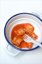 Ravioli with tomato sauce in bowl with plastic fork