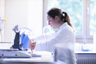 Young laboratory assistant with food sample works in a laboratory with laboratory equipment