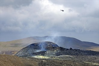Helicopter over smoking volcanic crater Fagradalsfjall