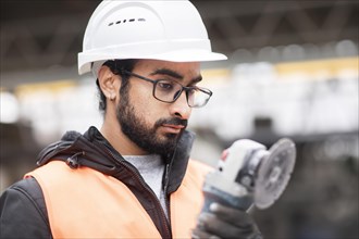 Technician with beard and helmet works in a workshop