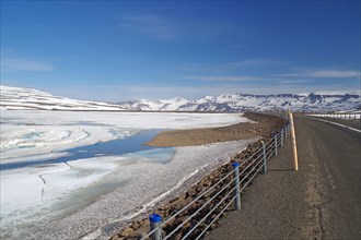 Road leads through barren mountain landscape with snow and ice