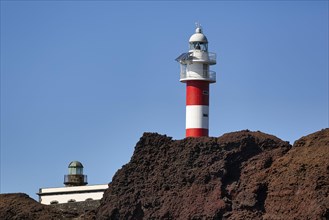 Red and white lighthouse on rocky coast