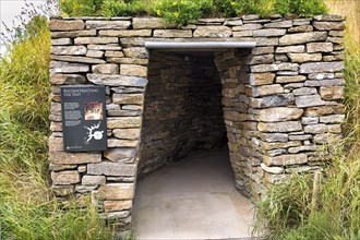Entrance to prehistoric house with information board