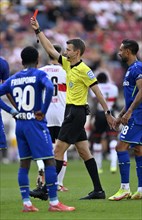 Referee Benjamin Cortus reaches into right hip pocket and pulls out red card